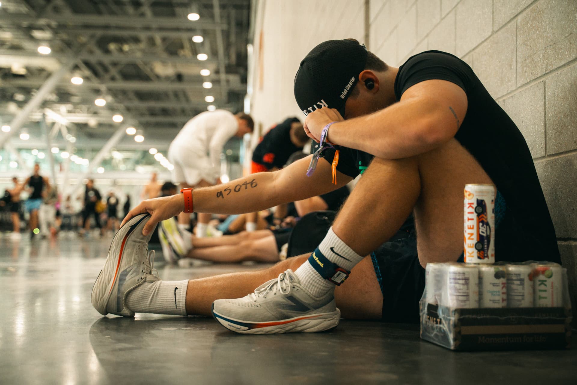 Adrian sitting against a wall at a race beside a case of Kenetik